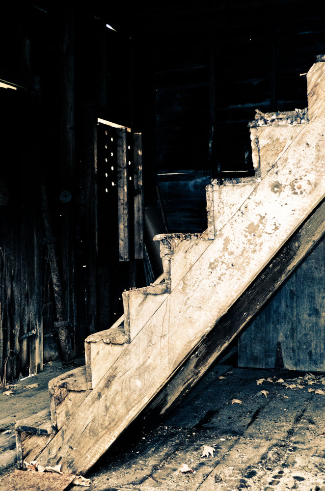 A decayed wooden staircase in a dark, abandoned building, covered in dust and debris. Image titled 'I Love You: A Paranormal Puzzle,' a journal entry in Candle Face Chronicles.